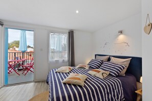 A bedroom with a bed, pillows, a bedside table, a wall-mounted light, and a view of the outside balcony. - Bed and Breakfast 'Chambre 4' with Shared Terrace, Wi-Fi and Air Conditioning (Saint-Gervais)