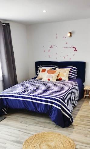 Una cama con ropa de cama a rayas, cabecera y almohadas decorativas.
