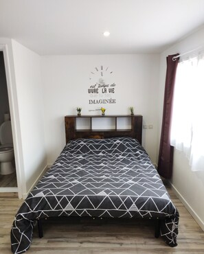 A bedroom with a bed, a wall-mounted shelf with plants, and a motivational quote. - Bed and Breakfast 'Chambre 1' with Shared Terrace, Wi-Fi and Air Conditioning (Saint-Gervais)