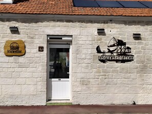 A building with a white brick exterior, a door, and a sign with a ship and the text 'LES GONE S'EN VENDEE'. - Bed and Breakfast 'Chambre 1' with Shared Terrace, Wi-Fi and Air Conditioning (Saint-Gervais)