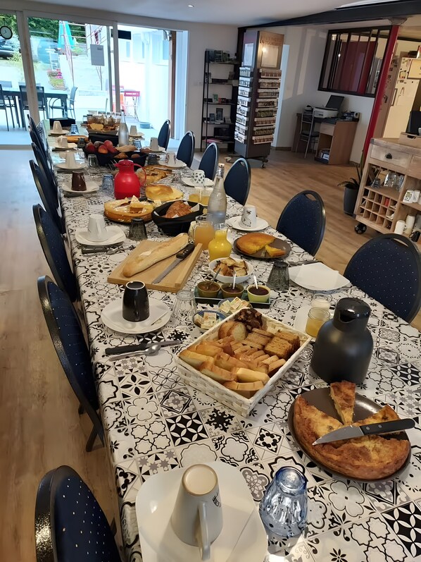 Zona de menjador amb una taula llarga preparada per l'esmorzar, incloent pa, pastissos i begudes.