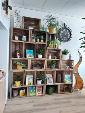 Una estantería de madera con varios niveles que contiene libros, plantas en macetas y objetos decorativos.