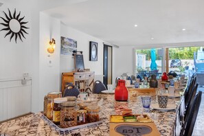 A dining area with a table set for a meal, a sun decoration on the wall, and a view of the outside. - Bed and Breakfast 'Chambre 3' with Shared Terrace, Wi-Fi and Air Conditioning (Saint-Gervais)