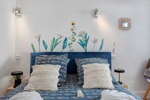 A bedroom with a bed, two bedside tables, a wall-mounted light fixture, and a decorative wall piece. - Bed and Breakfast 'Chambre 3' with Shared Terrace, Wi-Fi and Air Conditioning (Saint-Gervais)
