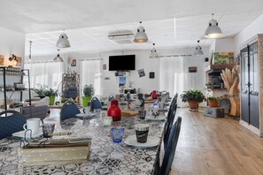 A modern living room with a tiled floor, a flat-screen TV mounted on the wall, and a dining area with a table set for four. - Bed and Breakfast 'Chambre 2' with Shared Terrace, Wi-Fi and Air Conditioning (Saint-Gervais)