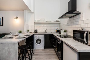 A modern kitchen with a built-in washing machine, a microwave, and a sink. - Jude`s Place 1 - 2 bedroomed apt/ 2 sofabeds (Merseyside)