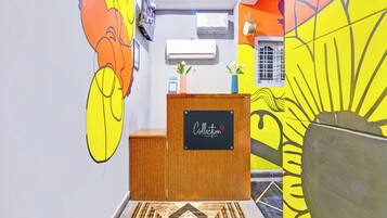 A reception desk with a chalkboard sign, a wall-mounted air conditioner, and a window with a grid pattern.
