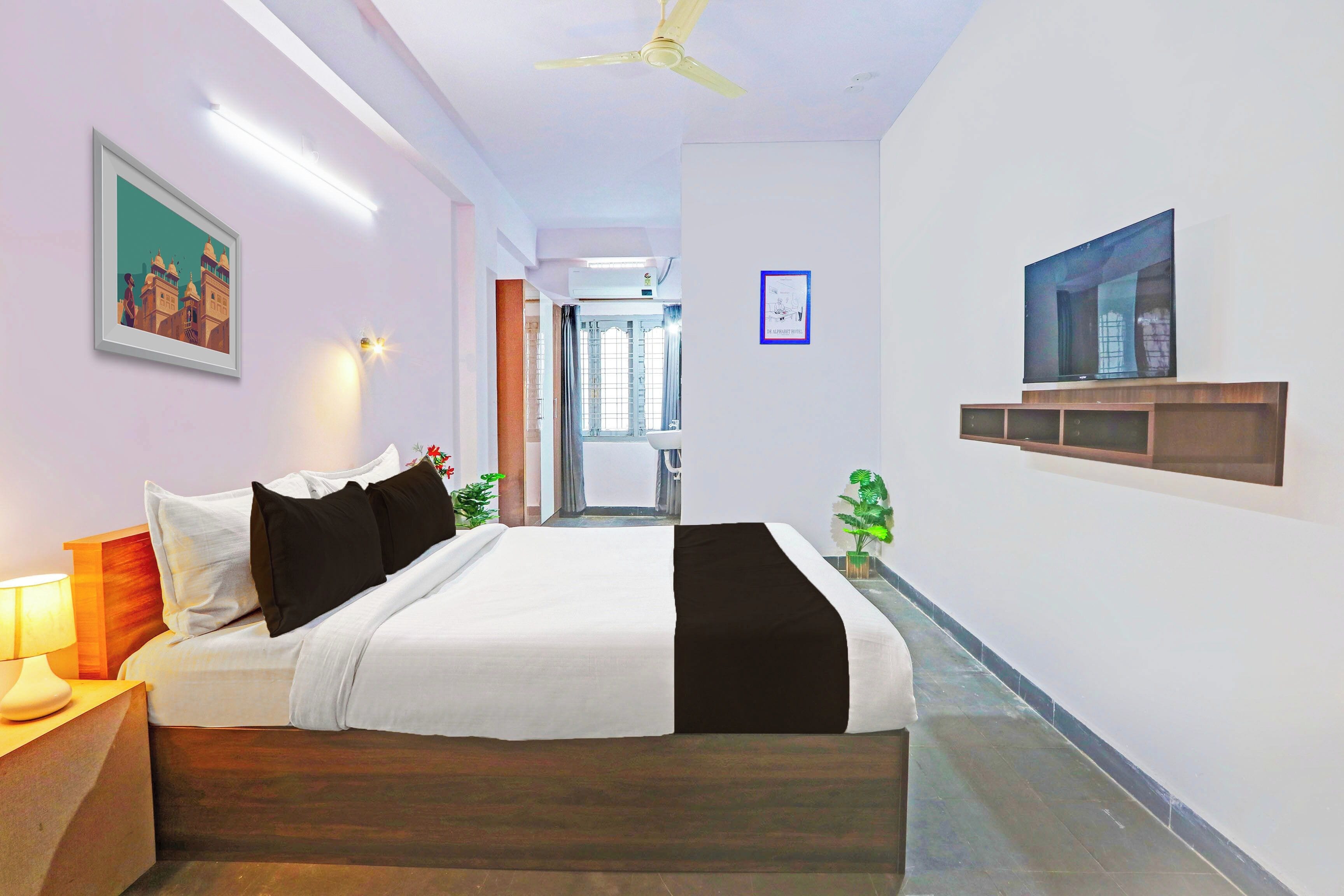 Una habitación de hotel con cama, lámpara de noche, televisión y un cartel en la pared.