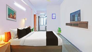 Una habitación de hotel con cama, lámpara de noche, televisión y un cartel en la pared.