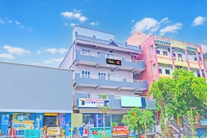 A multi-story building with various commercial establishments on the ground floor, including a pharmacy and a mobile service center. - Collection O De Alphabet Hotel UMCC (Hyderabad)