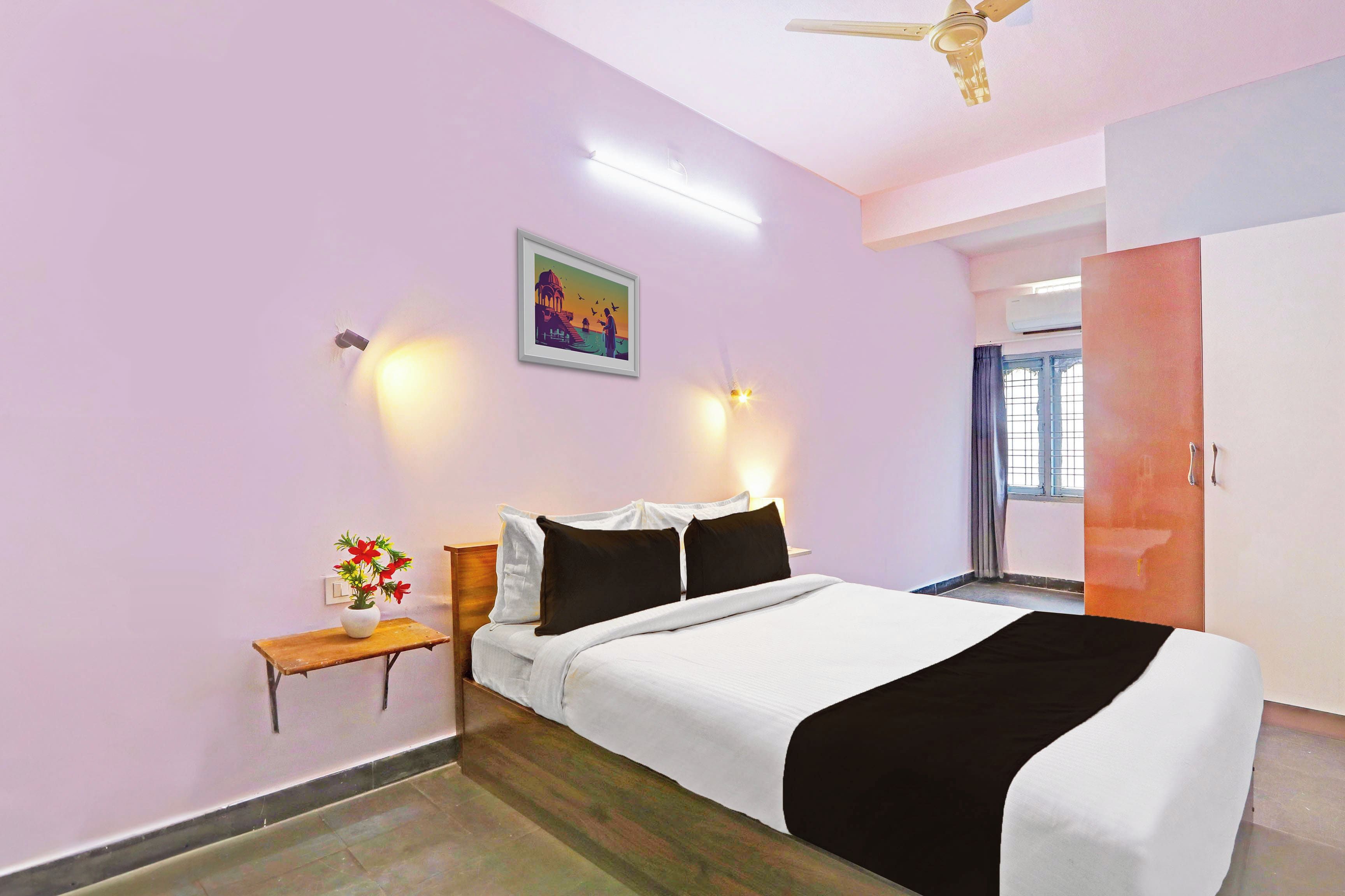 A bedroom with a bed, bedside table, wall art, and a ceiling fan.