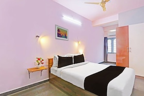 Un dormitorio con cama, mesita de noche, decoración en la pared y ventilador de techo.