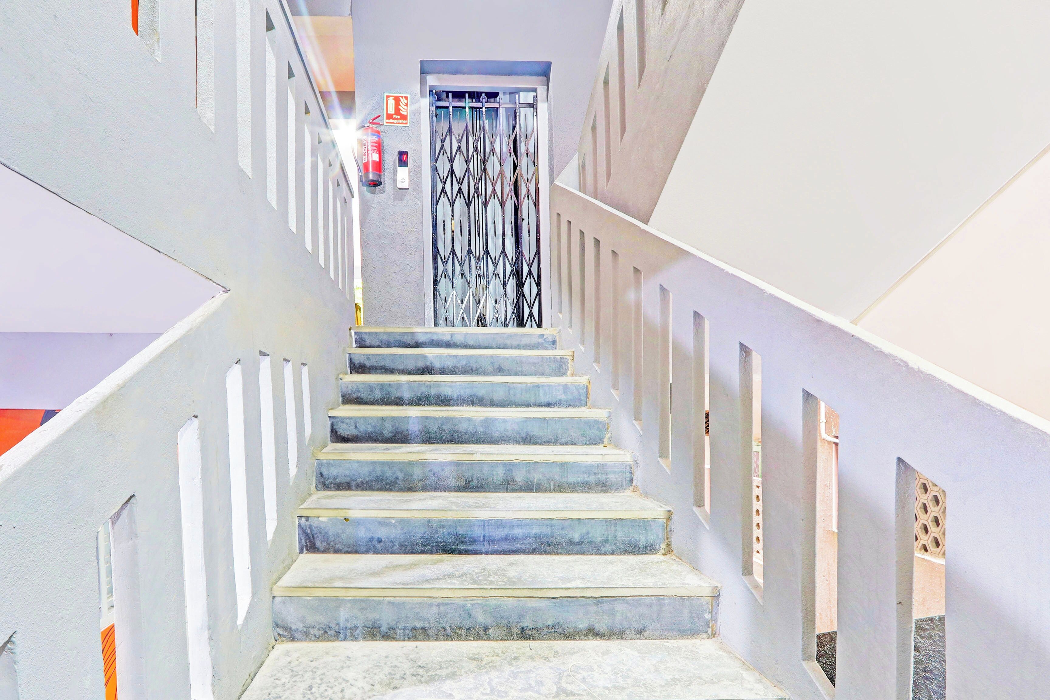A staircase with a fire extinguisher on the wall, leading to a door with a metal gate.