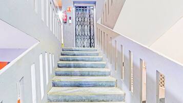 A staircase with a fire extinguisher on the wall, leading to a door with a metal gate.