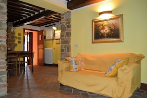 A cozy living room with a sofa, a dining table, and a fireplace. - Villa on organic farm between Chianti and Arezzo (Civitella In Val di Chiana)