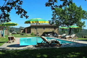 A stone building with a swimming pool, outdoor seating, and umbrellas. - Villa on organic farm between Chianti and Arezzo (Civitella In Val di Chiana)