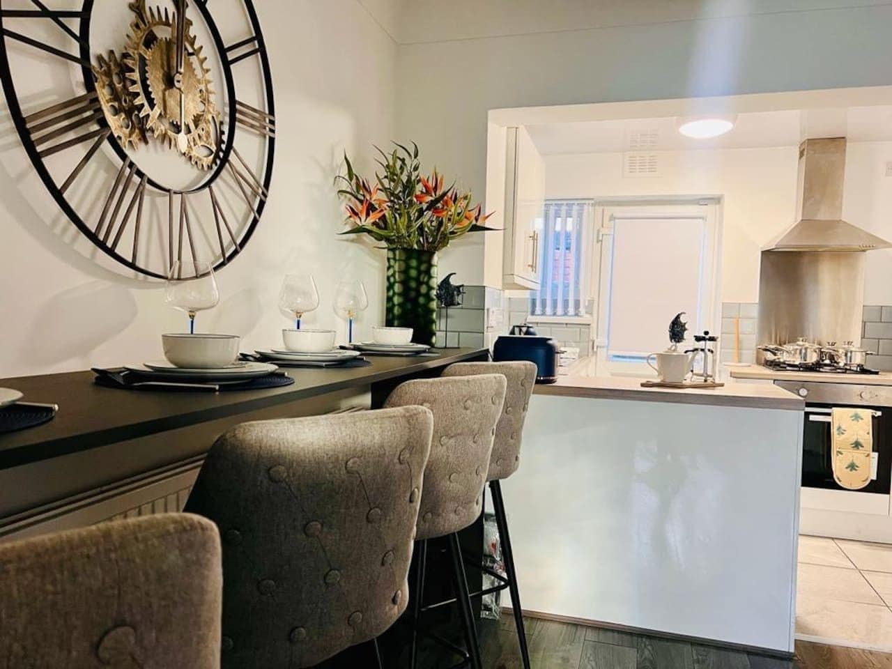 Une cuisine moderne dotée d’un îlot central, de tabourets de bar et d’une horloge décorative.