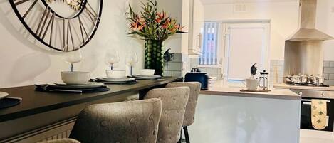 A modern kitchen with a central island, bar stools, and a decorative clock.
