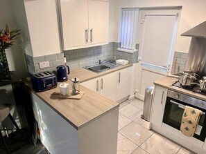 A modern kitchen with a central island, a built-in oven, and a window above the sink. - Cozy 2 bed home-15 mins to City/Anfield (Merseyside)