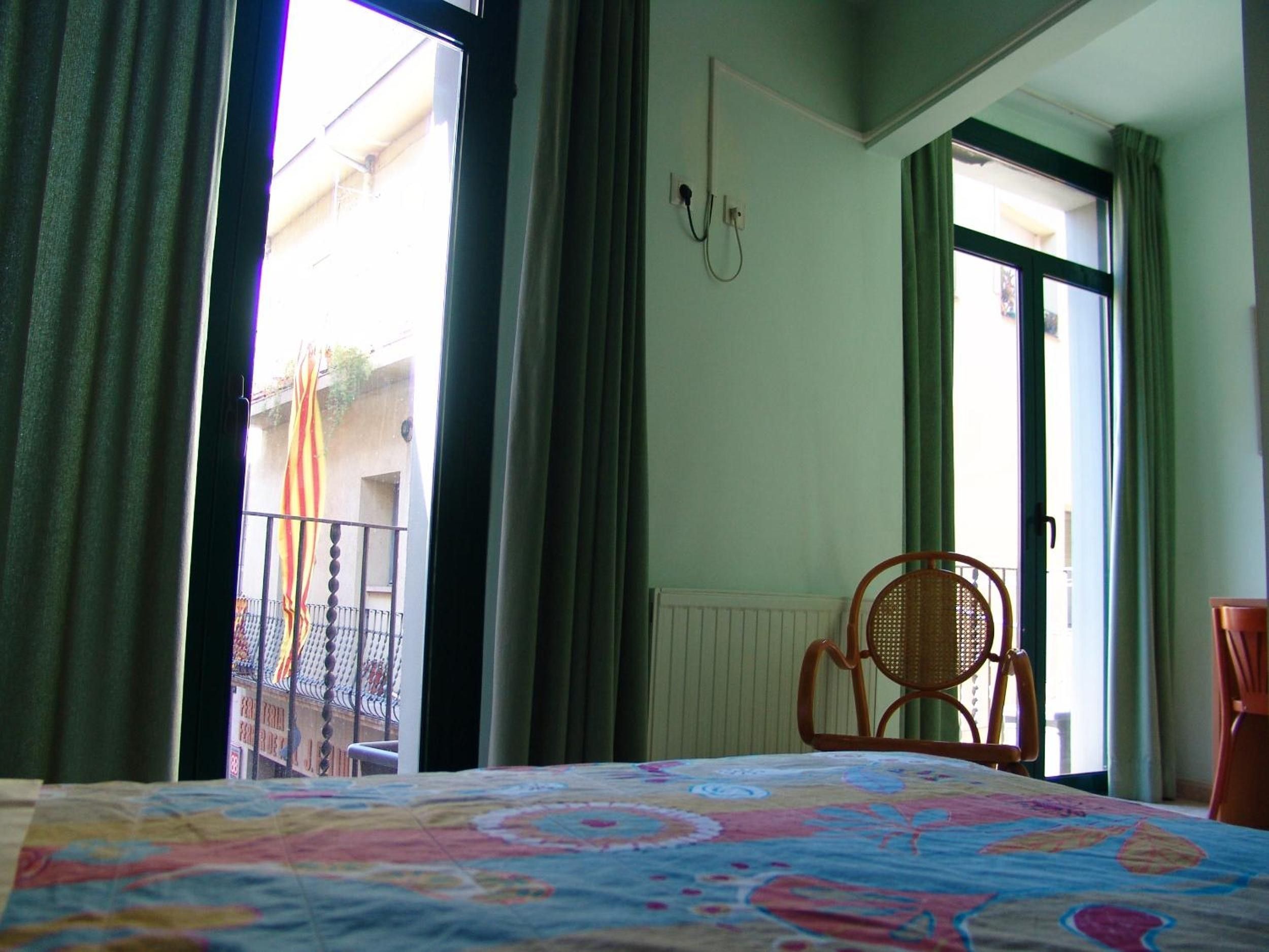 A hotel room with a bed, a chair, and a view of the outside.