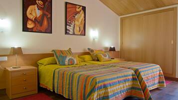 Un dormitorio con dos camas, un armario de madera, una mesita de noche con una lámpara y dos lámparas de pared.