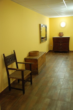 A room with a wooden chair, a chest of drawers, and a mirror on the wall.