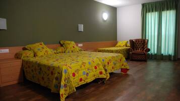 A room with two beds, a chair, and a window with curtains.