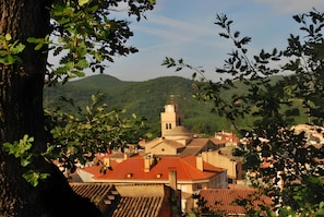 A town with a prominent church featuring a bell tower, surrounded by greenery and hills.