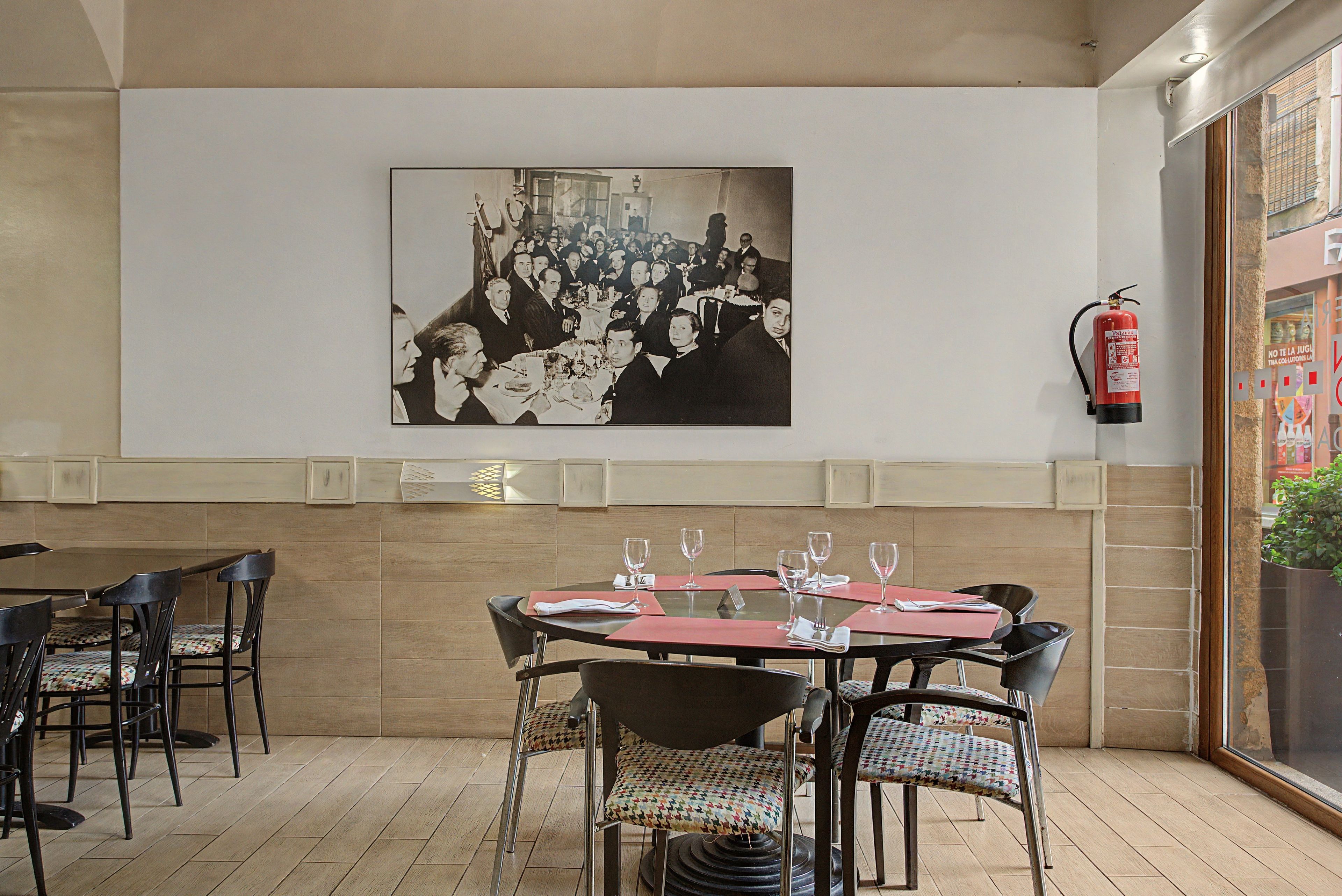 Interior de un restaurante con comedor, sillas, mesas y un extintor de incendios en la pared.