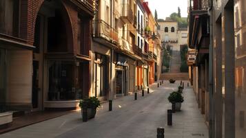 A narrow street with buildings on either side, featuring balconies and storefronts.