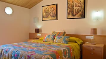 A bedroom with a bed, two bedside lamps, a nightstand, and two wall-mounted paintings.