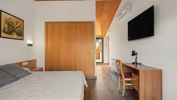 Un dormitorio con una cama, un escritorio, una silla, un televisor y un armario.