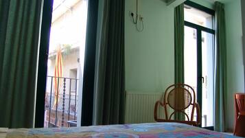 A hotel room with a bed, a chair, and a view of the outside.