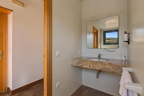 A bathroom with a granite countertop, a sink, a mirror, and a towel rack.