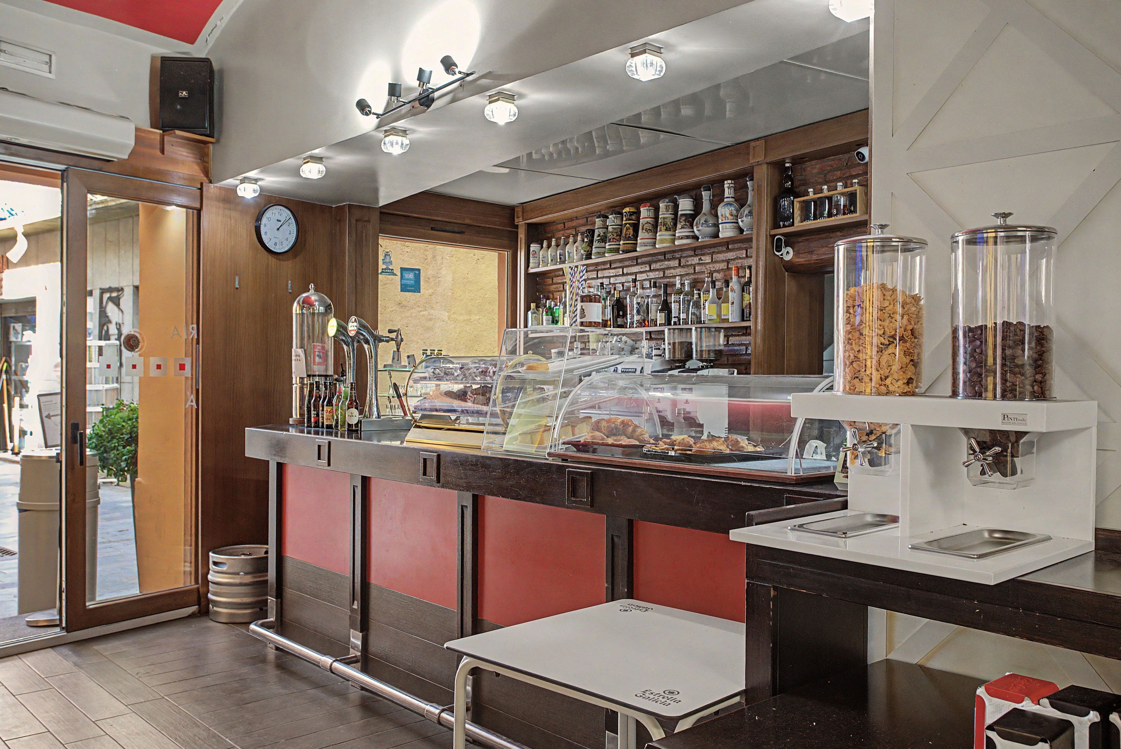 Interior de una cafetería con mostrador, zona de asientos y una exhibición de granos de café.