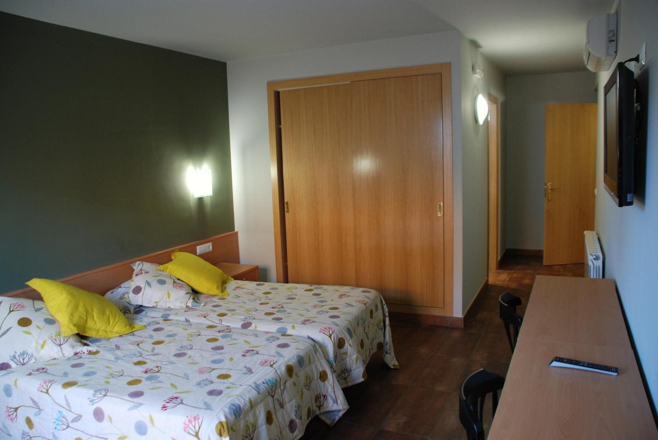 A room with two beds, a desk, a chair, a wardrobe, and a mirror.