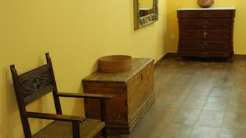 A room with a wooden chair, a chest of drawers, and a mirror on the wall.