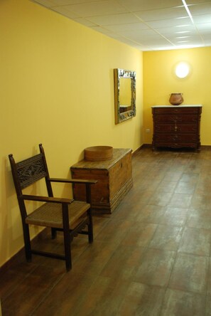 A room with a wooden chair, a chest of drawers, and a mirror on the wall.