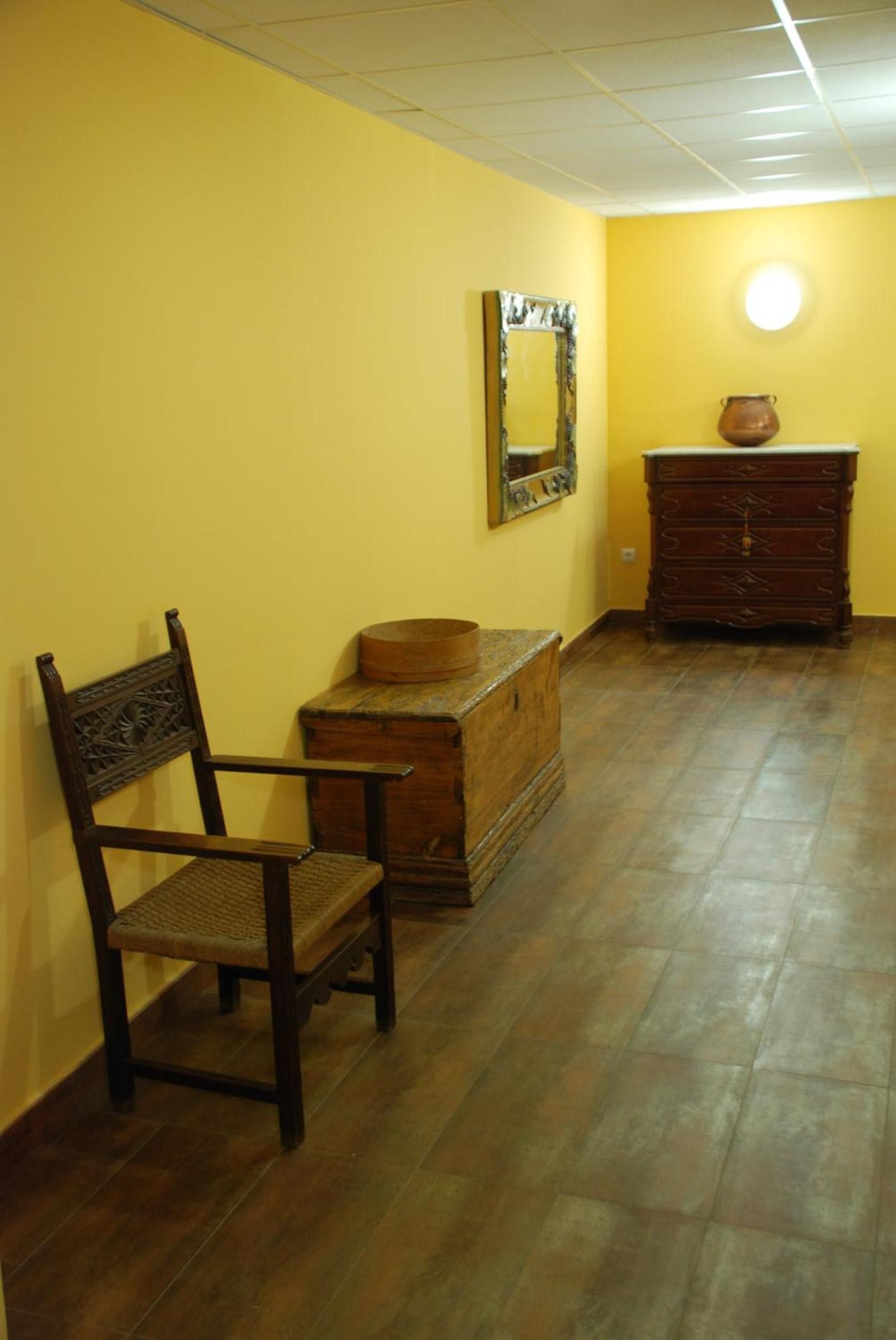 Una habitación con una silla de madera, un aparador y un espejo en la pared.