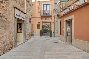 A narrow street with a hotel named 'HOTEL PIZZO' and a pharmacy 'FARMACIA' on either side.