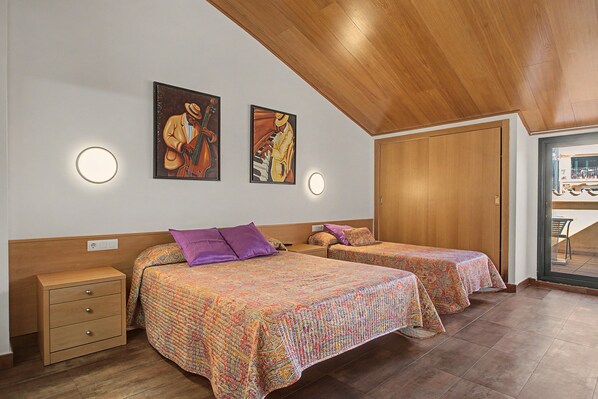A hotel room with two beds, a wooden ceiling, and artwork on the wall.