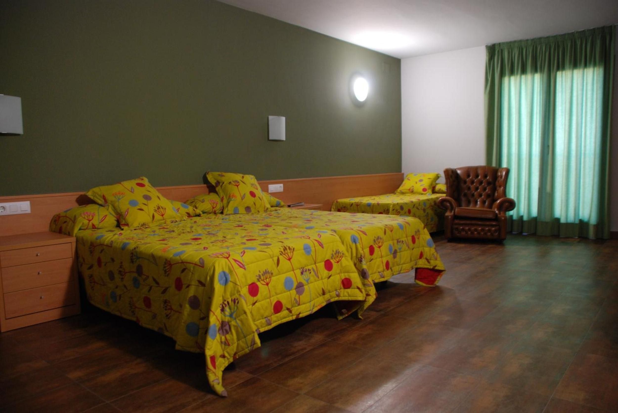 Quarto com duas camas, uma cadeira e janela com cortinas.