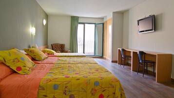 A hotel room with a large bed, a desk, and a TV.
