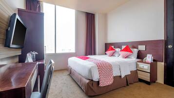 Una camera d'albergo con un letto, un comodino e una televisione a parete.