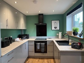 A compact kitchen with a built-in oven, a microwave, and a sink. - Myrtle Cottage-Hot tub. Sky TV. Relaxing. Romantic. Couples (Carlisle)