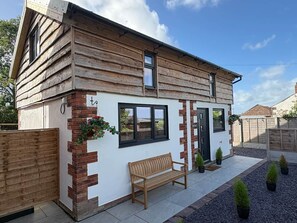 A wooden house with a brick wall, a bench, and potted plants. - Myrtle Cottage-Hot tub. Sky TV. Relaxing. Romantic. Couples (Carlisle)