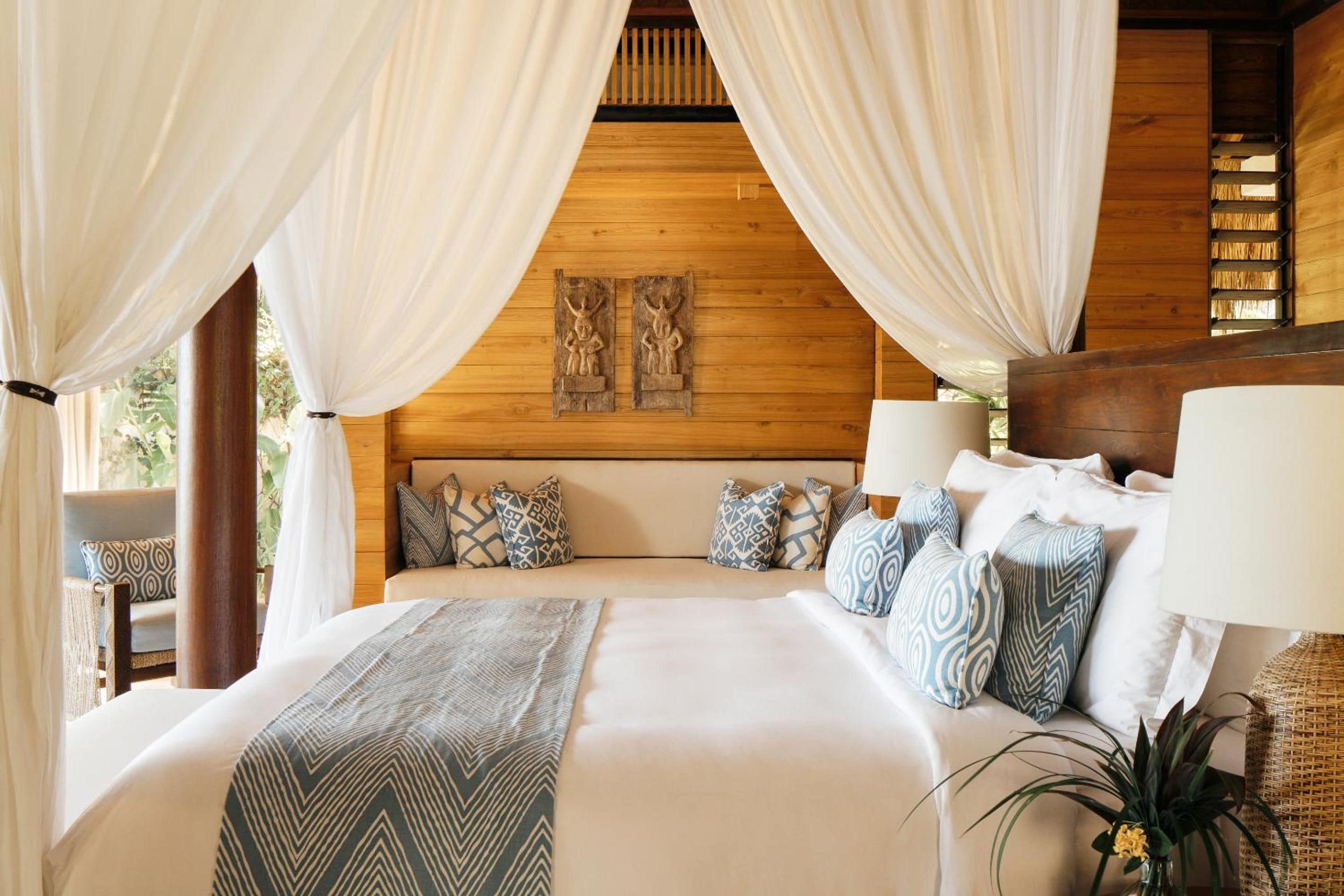 A bed with a headboard, multiple pillows, and a bedside table with a lamp.
