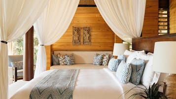 A bed with a headboard, multiple pillows, and a bedside table with a lamp.