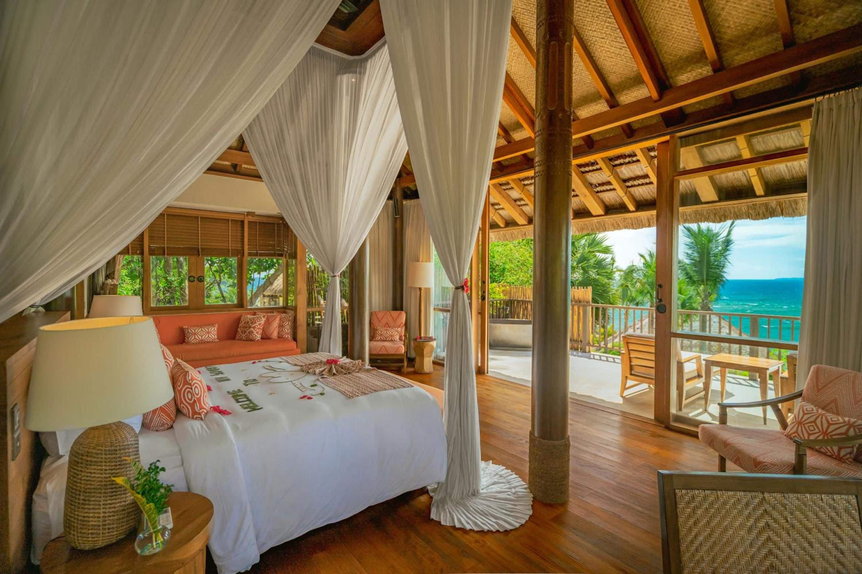 Ein Schlafzimmer mit einem Bett, einem Nachttisch, einer Lampe und Blick aufs Meer.