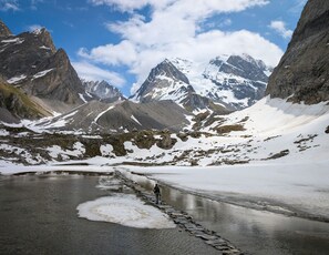 A mountainous landscape with snow-covered peaks and a frozen lake.